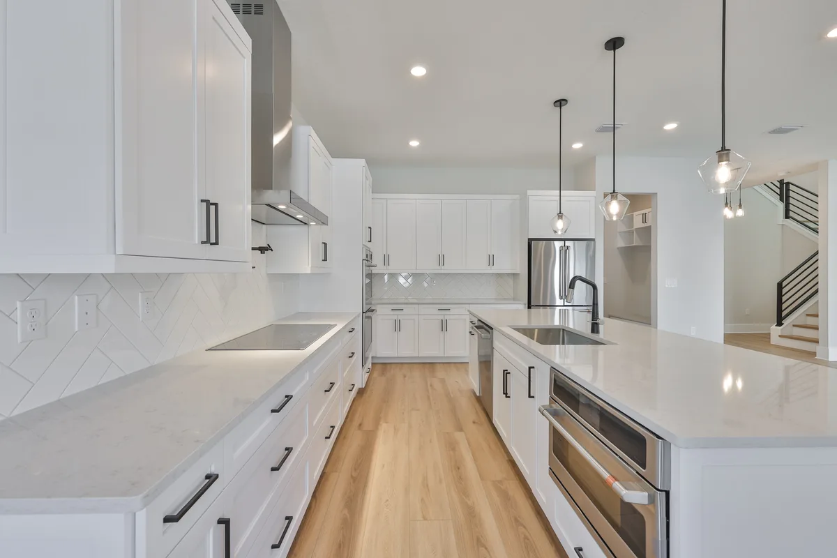Kitchen with waterfall island, pendant lighting and custom cabinetry in the BCL Homes build on W Paxton Ave