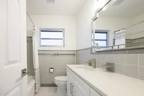 Updated bathroom with floating vanity, gold accents and tile accent wall.