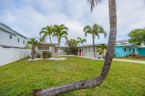 Tropical landscaping detail with lush palms and the home's soft coastal palette.