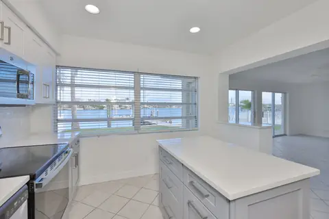 Bright kitchen with quartz island and large windows framing the waterfront view.