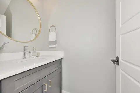 Powder bath with circular gold mirror, navy vanity and modern towel ring.