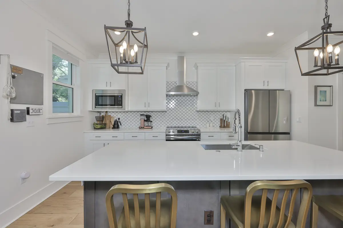Chef's kitchen with waterfall island, lantern pendants and arabesque tile backsplash.