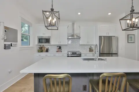 Chef's kitchen with waterfall island, lantern pendants and arabesque tile backsplash.
