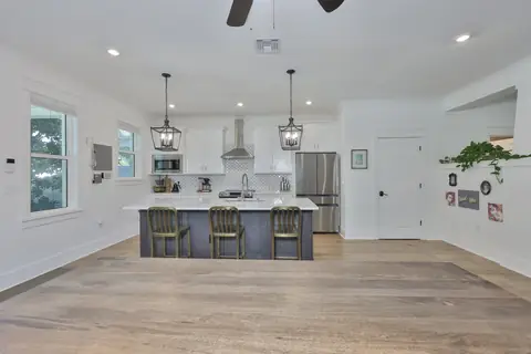 Alternate kitchen view showing the dark island, gold chair accents and range hood.