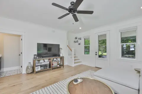 Open living room with modern ceiling fan, oak floors and double French doors to the porch.