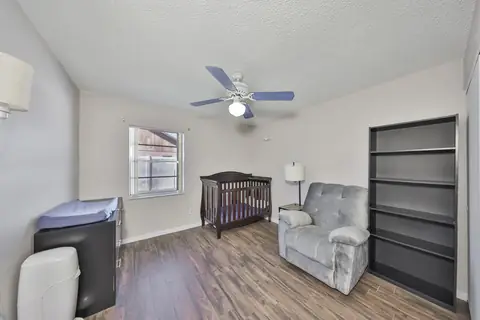 Secondary bedroom currently used as a nursery with wood-look plank flooring.
