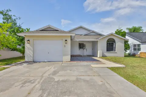 Classic white brick home with arched window, attached garage and welcoming front walkway.