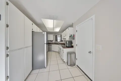 Galley kitchen with stainless appliances, painted cabinets and natural light.
