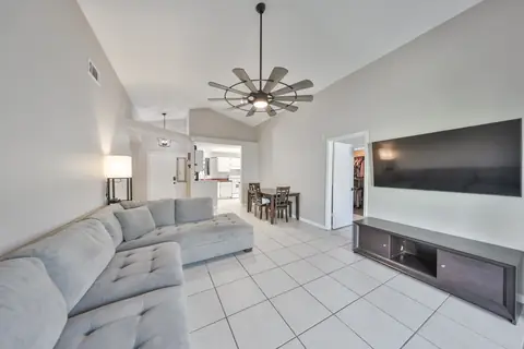 Vaulted-ceiling living and dining area with modern fan and tile flooring.