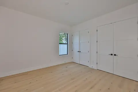 Secondary bedroom with oak plank floors and side-by-side closet doors.