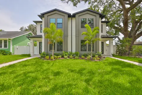 Front elevation showing the fresh sod, twin palms and contrast-color siding.