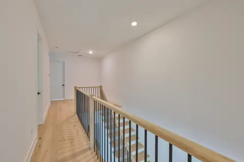 Upstairs landing with modern black-and-oak staircase and open-concept floor plan.