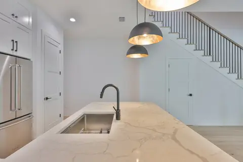 Kitchen detail showing the dramatic calacatta quartz island and dome pendants by the stairs.