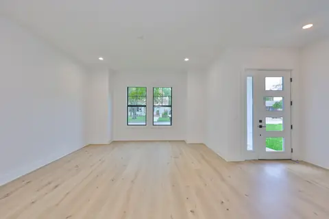 Sunlit living room with oversized windows, oak plank flooring and modern front door.