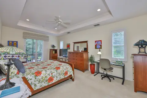 Generous primary suite with tray ceiling, sitting area and backyard-facing sliders.
