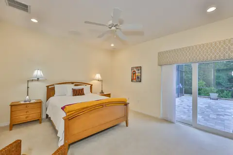 Bright guest bedroom with sliding doors leading to the pool patio and a paver deck.