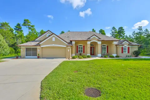 Front elevation of the single-story estate with tile roof, arched entry and three-car garage.