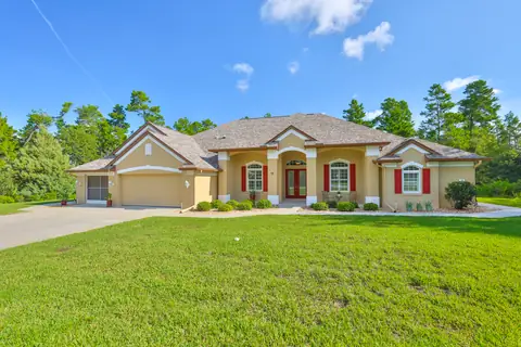 Daytime front elevation with arched windows, red shutters and three-car garage.