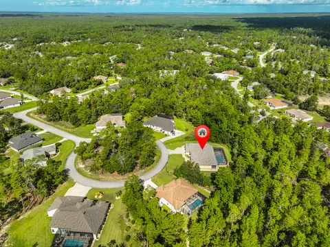 Zoomed aerial with locator pin showing the estate and its screened pool on the private lot.