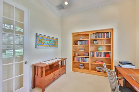 Home office/library with built-in bookshelves, French doors and neutral decor.