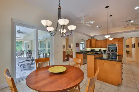 Eat-in kitchen with granite island, pendant lighting and sliders opening to the screened lanai.