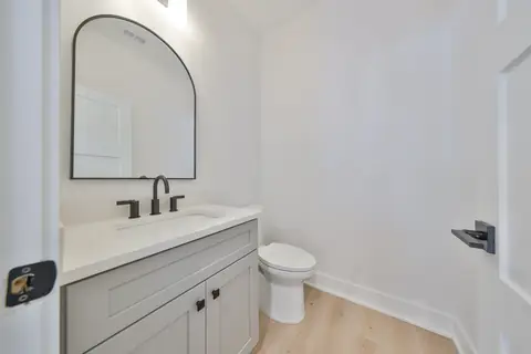 Powder bath with arched mirror, quartz counter and matte black fixtures.