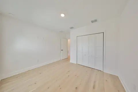 Secondary bedroom with built-in closet and warm oak plank flooring.