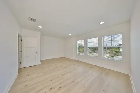 Spacious upstairs bedroom with three oversized windows, oak plank floors and fresh paint.
