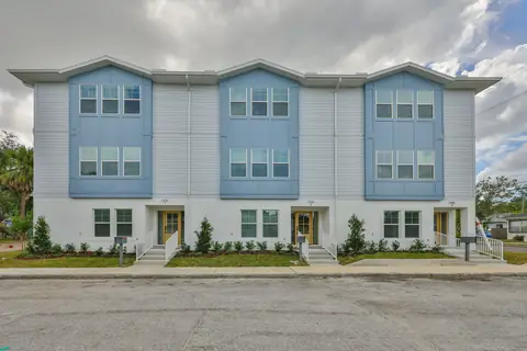 Three coastal-modern townhomes with blue and white siding and individual gated entries.