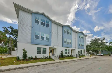 Angled street view of the townhome trio with blue-and-white siding and arching rooflines.