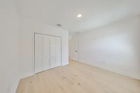 Sunlit upstairs hallway with oak floors and open stair rail.