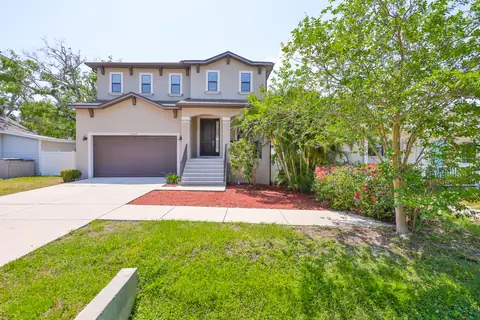 Two-story stucco home with peaked roofline, two-car garage and welcoming front walkway.