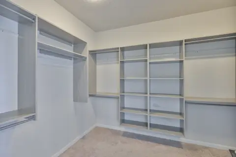Walk-in primary closet with custom built-in shelving and drawers.