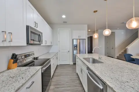 Bright kitchen with granite counters, globe pendants and stainless appliances.