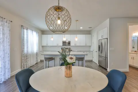 Staged dining nook overlooking the kitchen with globe chandelier and proteas centerpiece.