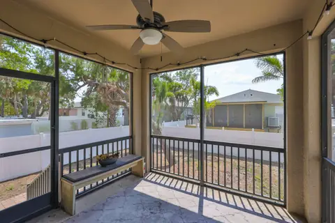 Screened covered lanai with ceiling fan, string lights and a built-in bench.