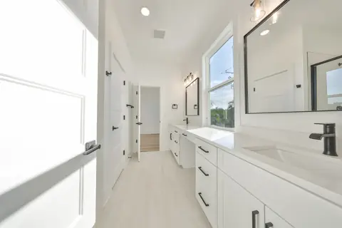 Spa-like primary bath with dual vanity, matte-black fixtures and abundant natural light.