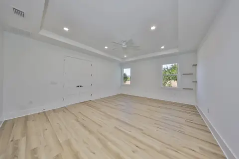 Spacious primary suite with tray ceiling and oak-look plank floors.
