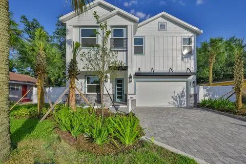 Daytime front elevation with white board-and-batten siding, second-story balcony and two-car garage.