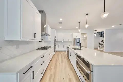 Chef's kitchen detail with herringbone tile backsplash, gas range and stainless hood.
