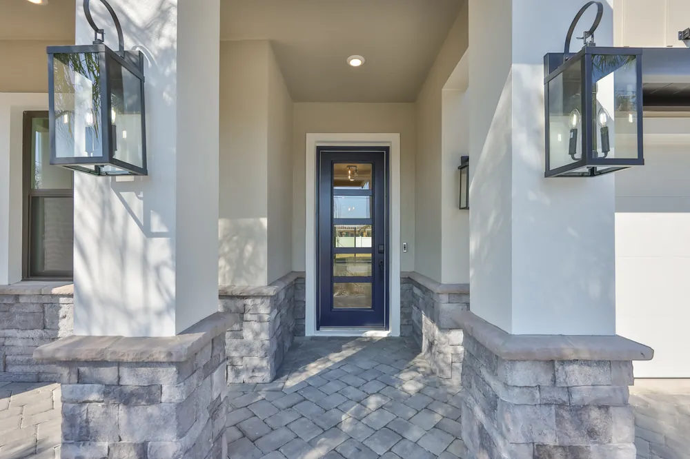 Covered entry with stone detail and lantern sconces on a South Tampa custom build